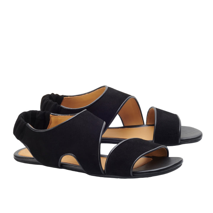 Die CISQA Black Sandalen von ZAQQ präsentieren ein minimalistisches Design mit schwarzer offener Zehenpartie, breiten überlappenden Riemen und einer elastischen Rückseite. Sie verfügen über eine flache Sohle und ein sichtbares hellbraunes Innenfutter und verbinden Komfort nahtlos mit Stil.