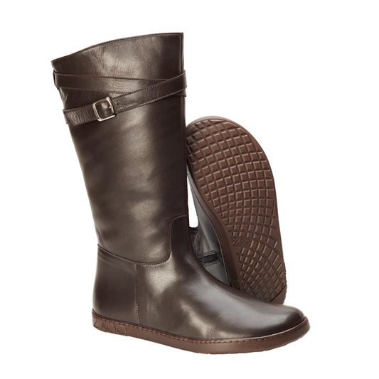 Wir präsentieren den ATTRAQT Winter Brown von ZAQQ: Diese hohen, dunkelbraunen Lederstiefel haben einen Schnallenriemen und eine flache Sohle, ideal für Ihre Winterstiefel-Bedürfnisse. Wenn ein Stiefel aufrecht steht und der andere auf der Seite liegt, können Sie das strukturierte Sohlendesign sehen, das Tragekomfort garantiert und ein fast barfußgefühlvolles Erlebnis bietet.