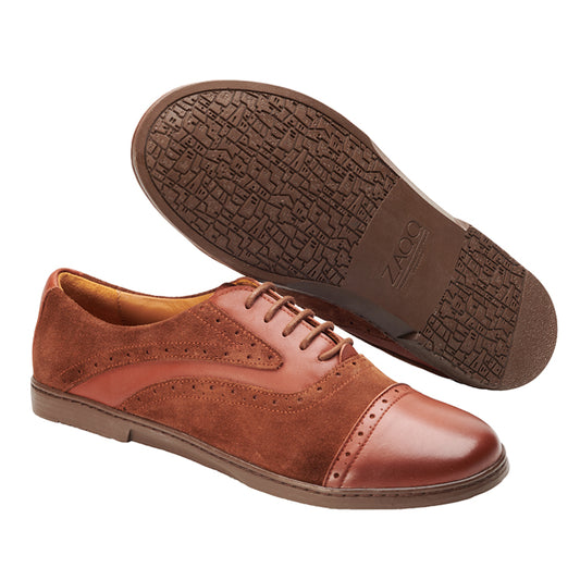 Wir präsentieren den QENTLE Brown von ZAQQ, ein exquisites Paar Oxford-Schuhe aus braunem Leder und Wildleder. Dieses Design zeichnet sich durch aufwendige Brogue-Details aus, wobei ein Schuh auf der Seite liegt, um die strukturierte Sohle mit dem geprägten Markennamen ZAQQ zu präsentieren. Diese Schuhe sind fachmännisch aus hochwertigem Kalbsleder gefertigt und verkörpern als Teil der Business-Kollektion Eleganz und Raffinesse.