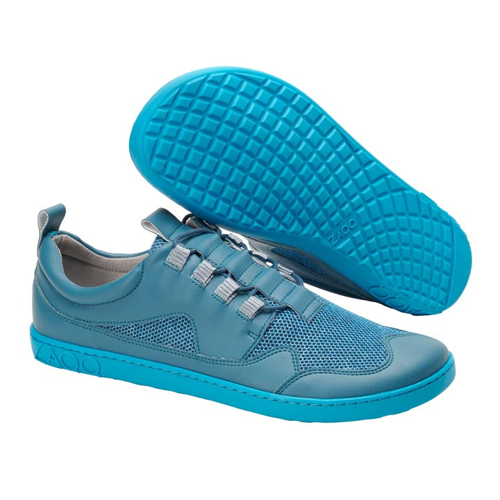 Ein Paar lässige QARLY Turquoise-Sneaker von ZAQQ besticht durch eine stilvolle Kombination aus Mesh und Leder, ergänzt durch elastische Schnürsenkel und eine strukturierte Sohle. Ein Schuh steht aufrecht und betont das schlanke Design, während der andere schräg positioniert ist, um das komplizierte Sohlenmuster zur Geltung zu bringen.