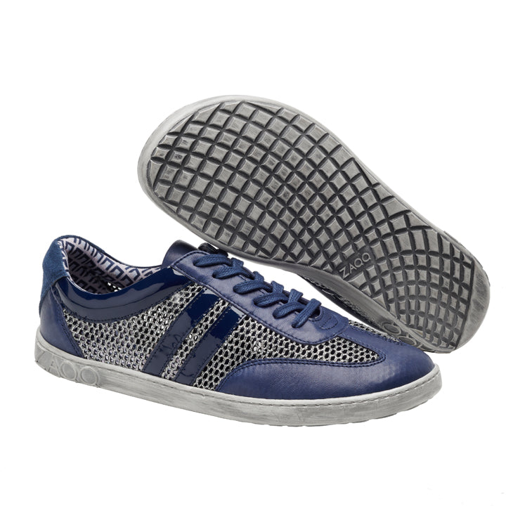 Wir präsentieren die QIMBERLY Blue-Sneaker von ZAQQ, ein stylisches Paar mit atmungsaktivem Mesh-Obermaterial, das mit dunkelblauen Streifen verziert ist. Diese Barfuß-Sneaker mit grauen Sohlen in Gittermuster und Ziernähten vereinen mit ihrem gemusterten Innenfutter Komfort und Flair perfekt.