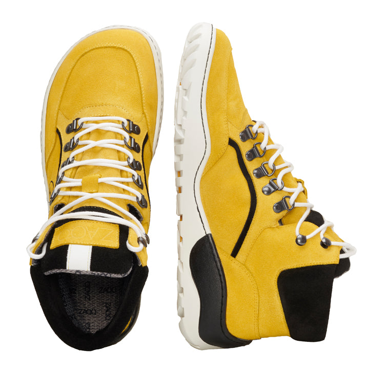 Ein Paar TERRAQ Yellow Waterproof Wanderstiefel von ZAQQ hat eine leuchtend gelbe Farbe mit weißen Schnürsenkeln und schwarzen Akzenten an Ferse und Zunge. Die dicken, weißen Sohlen verleihen ihnen ein robustes, sportliches Aussehen. Diese Stiefel stehen Seite an Seite und sind bereit, jedes Outdoor-Abenteuer zu meistern.