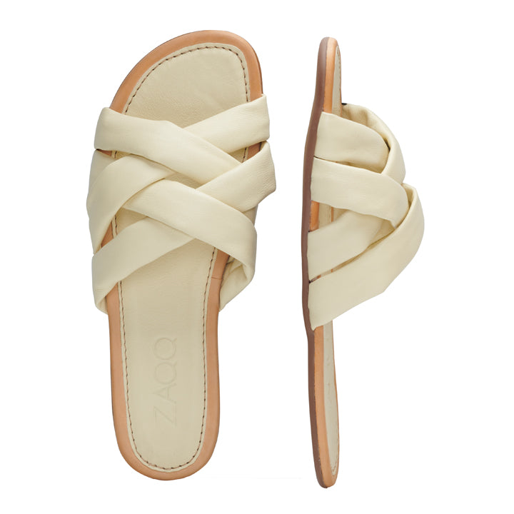 Wir präsentieren die ALAQ Beige von ZAQQ: Diese Sandalen haben überkreuzte Riemen aus Nappaleder in Beige und werden durch eine hellbraune Kautschuksohle ergänzt. Eine Sandale ist von oben zu sehen, während die andere von der Seite präsentiert wird.