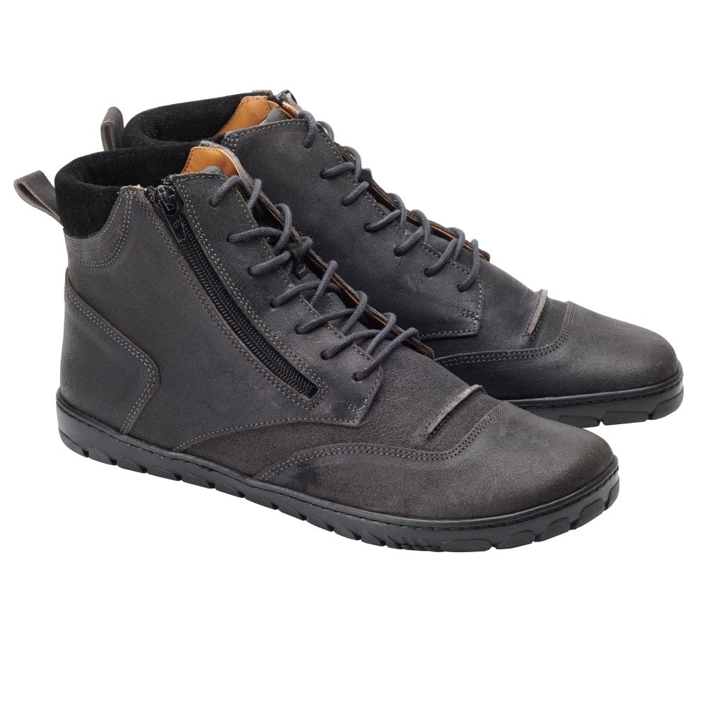 Die PARQER Dark Grey High-Top-Schuhe aus Veloursleder von ZAQQ haben Reißverschlüsse an den Seiten, schwarze Sohlen und einen strukturierten, abgenutzten Look. Diese Barfußschuhe haben ein teilweise sichtbares braunes Innenfutter und werden auf einem weißen Hintergrund präsentiert.