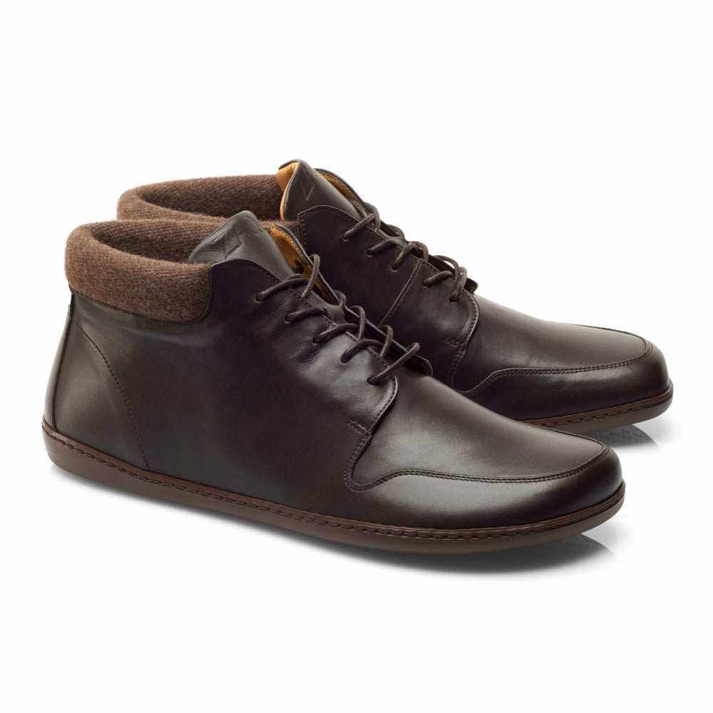 Die NEWQUAY Brown High-Top-Stiefeletten von ZAQQ zeichnen sich durch ein schlichtes, modernes Design mit dunkelbraunem Nappaleder und braunen Schnürsenkeln aus, ergänzt durch ein weiches hellbraunes Innenfutter. Das Produkt wird auf einem weißen Hintergrund präsentiert, der diese halbhohen Stiefel hervorhebt.