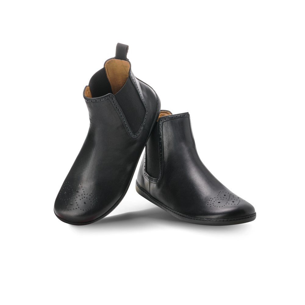 Ein Paar kleiner ZAQQ EQUITY Brogue-Stiefel aus schwarzem Leder mit dekorativen Perforationen an den Zehen ist vor einem weißen Hintergrund zu sehen. Diese Stiefel aus hochwertigem Nappaleder haben ein braunes Innenfutter und elastische Seitenteile für bequemes Tragen.